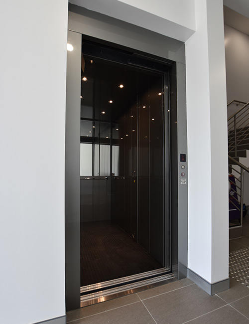 Open doors and black interior of a DDA compliant commercial lift