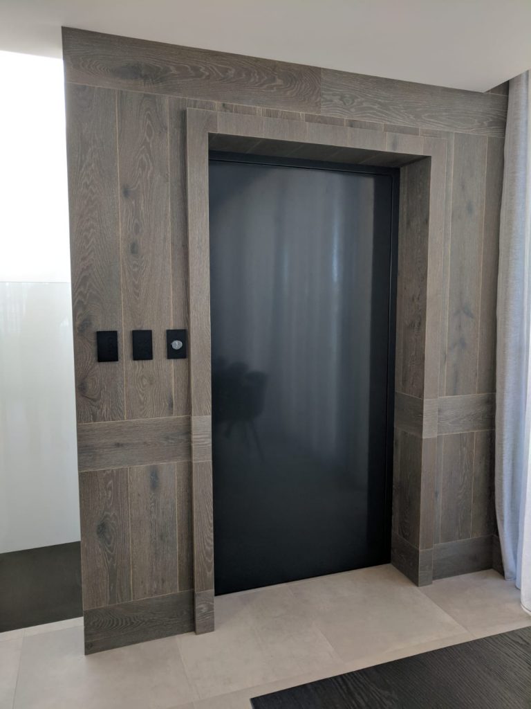 classic home lift built into feature wall with dark reflective door