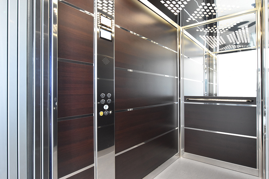 commercial lift with brown panel walls, a mirror at the back and silver details.