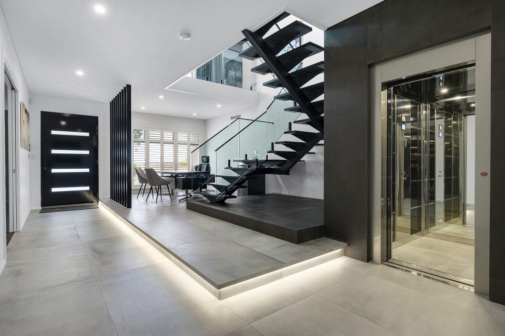 beautiful monochromatic home design with a dark staircase and feature elevator