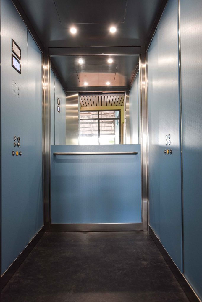 a school elevator internal cabin with blue walls and metal accents.