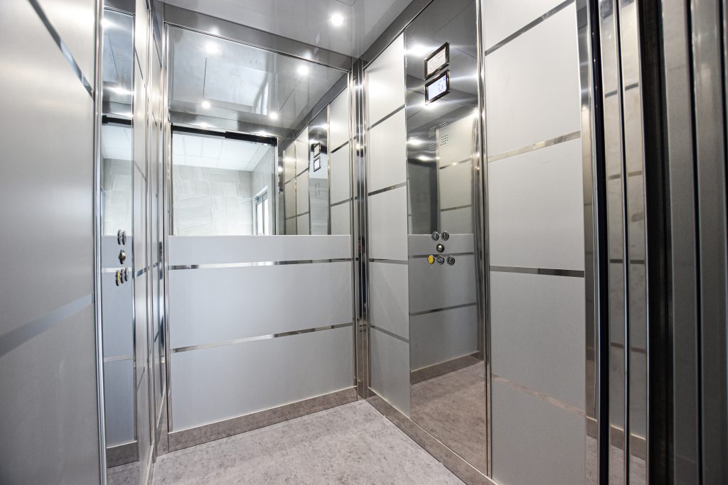 elevator cabin interior with a half length mirror on the back wall.