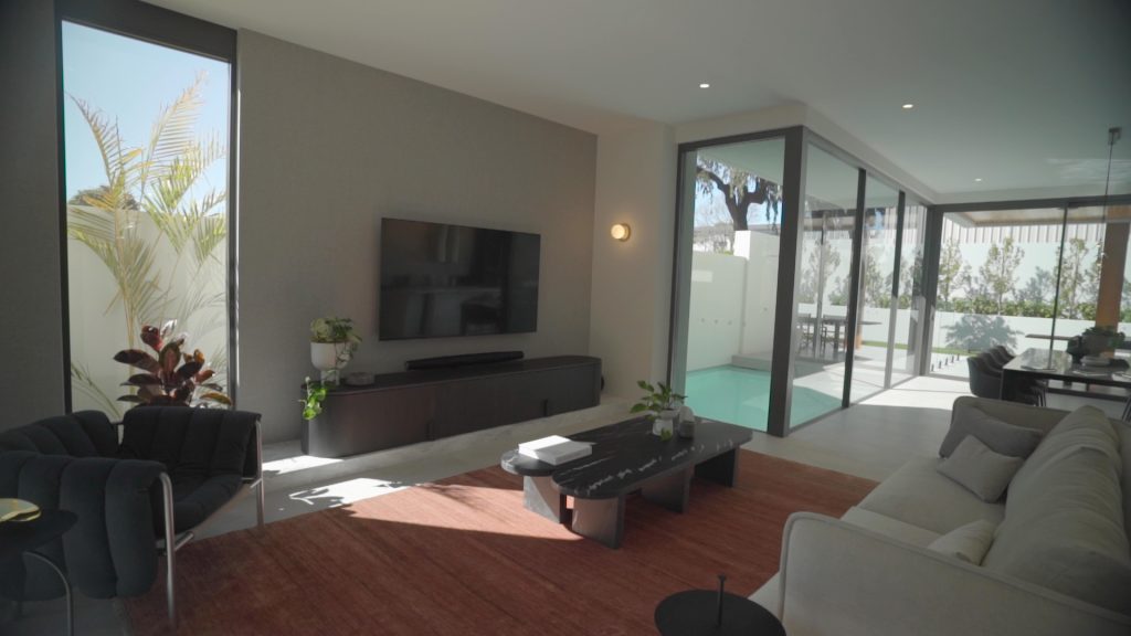 an open plan living room with big windows and modern furniture.