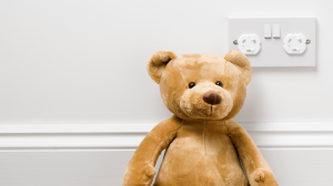 teddy bear in front of wall with electrical plug point