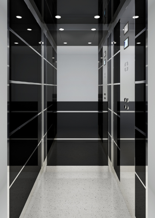 The interior of a modern, sleek elevator with glossy black walls and horizontal metallic strips creating a grid pattern. The ceiling has recessed lighting, and the floor is a speckled white material. The control panel on the right wall features buttons and a small display screen. The overall design is minimalist and contemporary.
