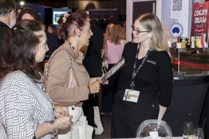 West Coast Elevators team member speaking with visitors at the Ink & Ivory event in Perth, engaging attendees with brochures and a promotional display including a lucky draw.