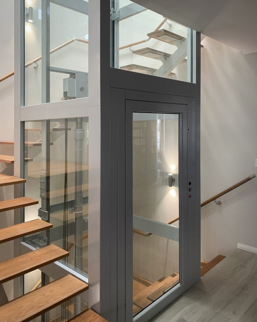 Modern residential lift beside wooden staircase
