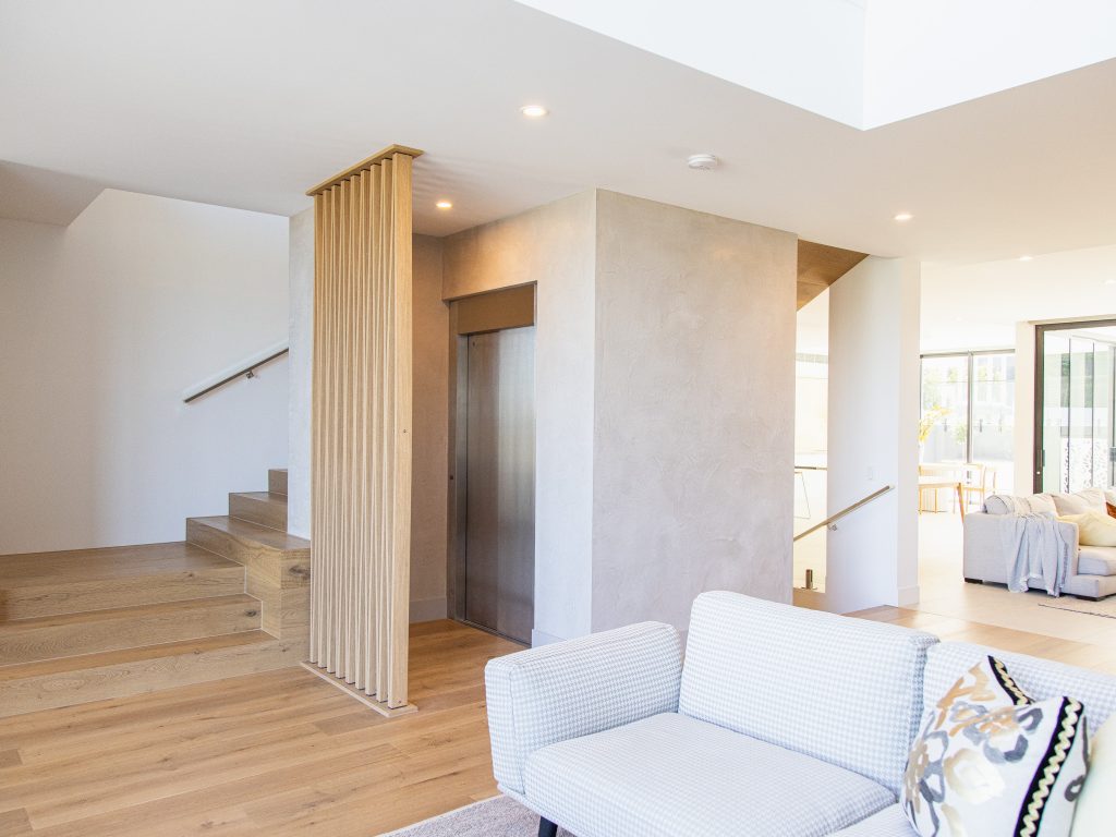 Modern living room with wooden stairs and lift.