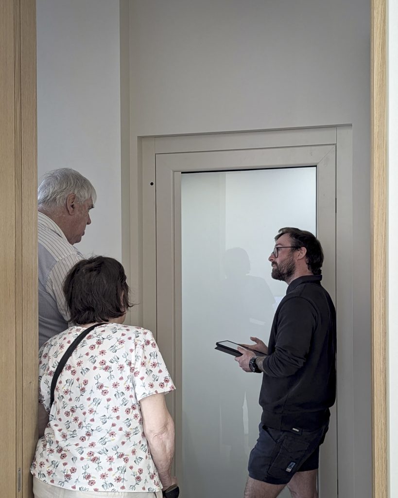 Three people discussing near a door.