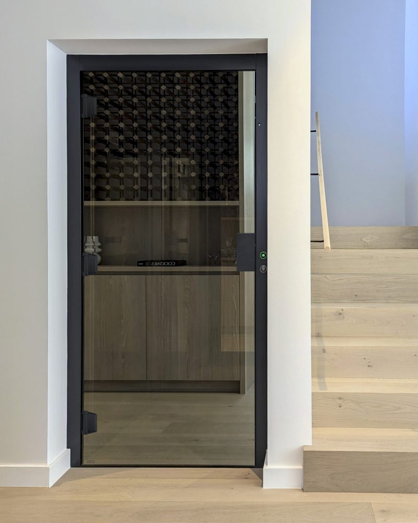 Glass door beside wooden staircase indoors.