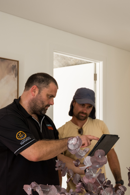 Two men discussing on a tablet indoors.