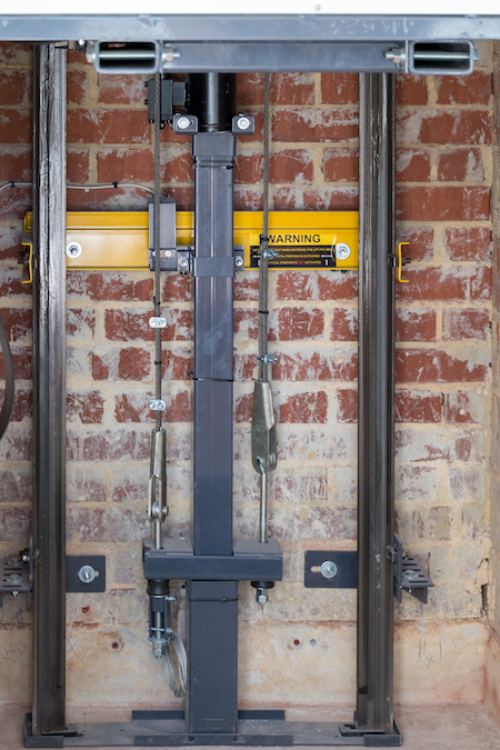 elevator door counterweight system against brick wall.