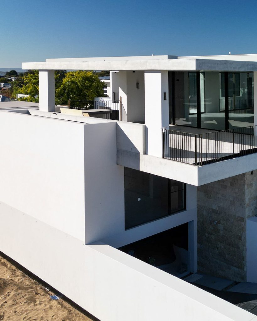 Modern white coastal home with balcony and glass