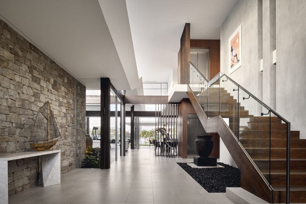 Modern residential lift in two-storey home with timber staircase and stone wall