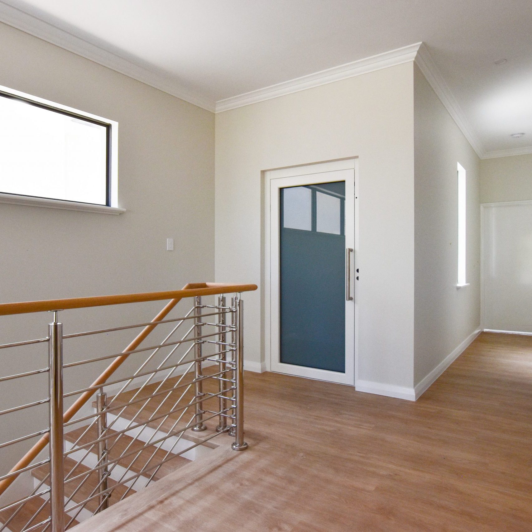 Residential lift with white framed door in Applecross. Located next to stairs.