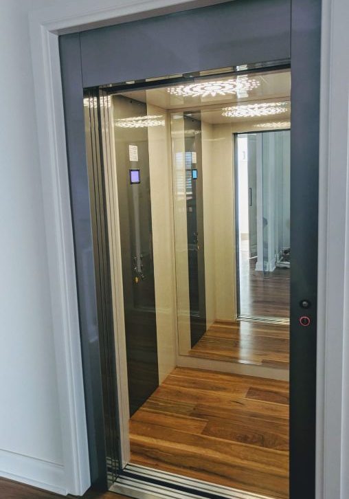 Open door of a residential lift with wooden floor