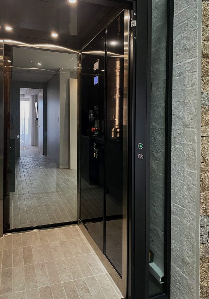 Modern glass residential lift in tiled hallway