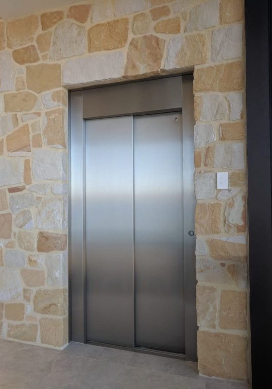 Closed doors of a residential lift with stone surrounding