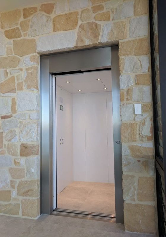 Open doors of a residential lift with stone surrounding