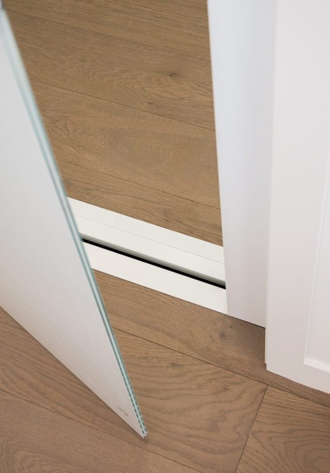 Frameless glass door panel above timber floor