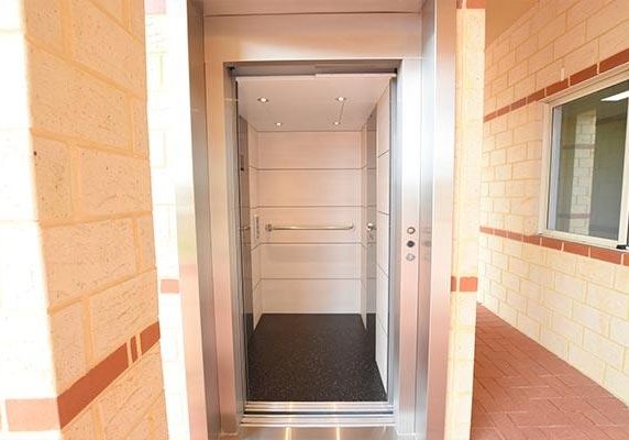 open doors of a lift with cream brick surrounds