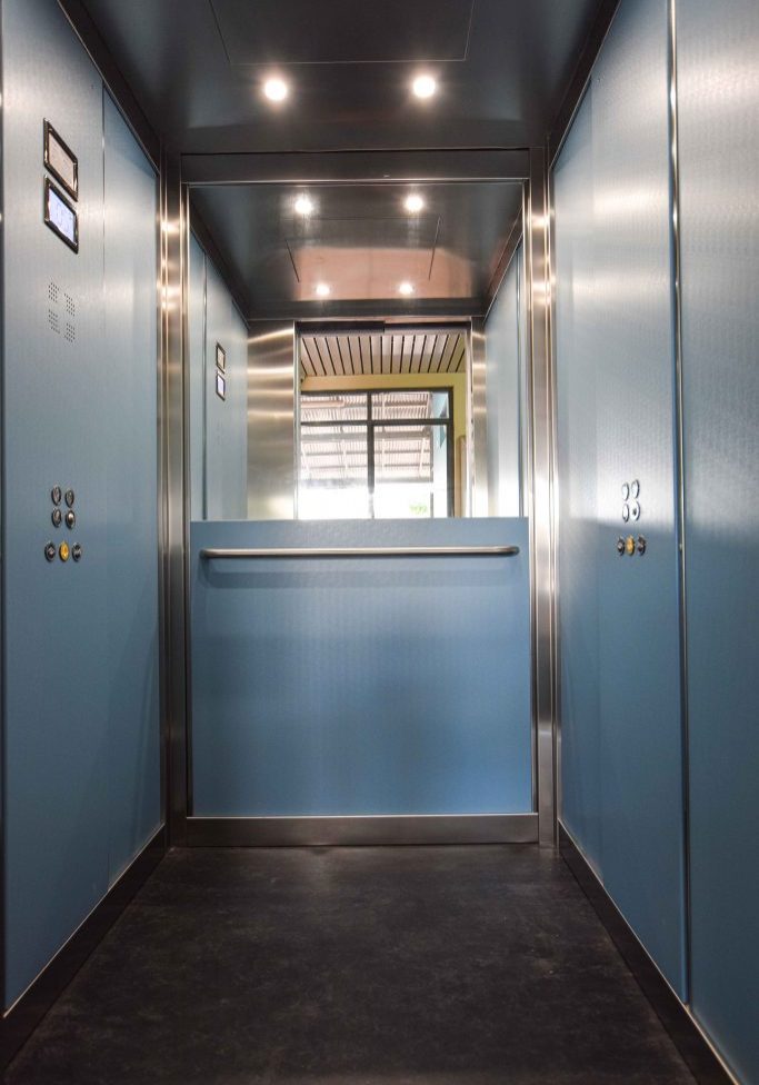 a school elevator internal cabin with blue walls and metal accents.